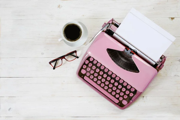 Máquina de escribir rosa antigua de la década de 1950 con papel en blanco, café y vasos en madera rústica pintada de blanco, espacio para copiar, vista de ángulo alto desde arriba — Foto de Stock