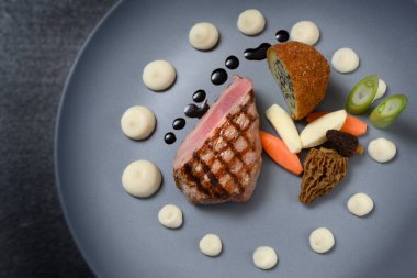 kavrulmuş dana eti, morels, sebze ve kızarmış patates koyu bir masa üzerinde mavi gri plaka üzerinde soğan tohumu ile doldurulmuş ile şenlikli yemek, kopya alanı, yukarıdan yüksek açı görünümü