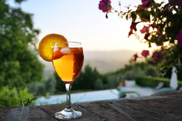 Spritz Veneziano cocktail drink on a garden wall in front of an idyllic landscape, sunset sky with copy space — Stock Photo, Image