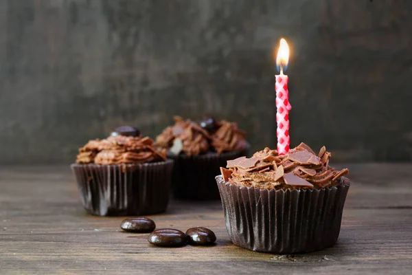 Κεκάκια σοκολάτας με ένα φλεγόμενο κερί σε ρουστίκ ξύλο, γκρι vintage φόντο με χώρο αντιγραφής — Φωτογραφία Αρχείου