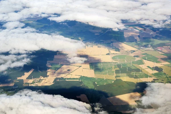 Vista aérea a través de las nubes a un parque eólico con muchas turbinas eólicas en un paisaje agrícola —  Fotos de Stock
