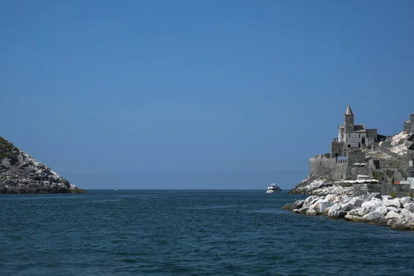 sea passage between the headland of Porto Venere with the famous Saint Peter\'s Church and the island of Palmaria, the gate to the Cinque Terre, Liguria, Italy, blue sky with copy space