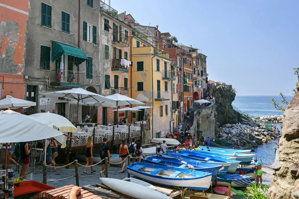 RIOMAGGIORE, ITALY, JULY 5, 2019: Blue fishing boats in Riomaggiore, one of the Cique Terre hill cities with colorful houses and many tourists on the Mediterranean sea coast in Liguria, Italy — Stock Photo, Image
