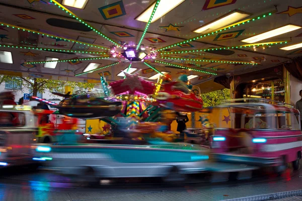 Carrusel infantil con coches y aviones en el mercado de atracciones navideñas, exposición prolongada con movimiento borroso, fondo abstracto, espacio para copiar —  Fotos de Stock