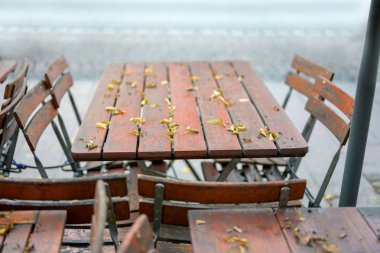 sezon sonu, kullanılmayan açık ahşap ve metal sonbaharda bir sokak restoranından tohum ve yaprakları aşağı düşmüş ile