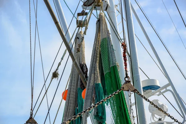 Redes e cordas nos guindastes de um barco de pesca contra o céu azul com nuvens — Fotografia de Stock