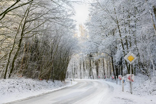 Gevaarlijke curve op een ijzige landweg door het besneeuwde winterbos, veiligheidsrij concept, kopieer ruimte — Stockfoto