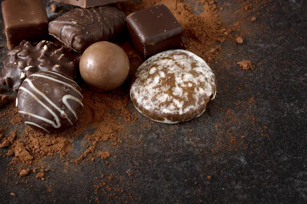 Chocolate, galletas y pralinés sobre un fondo de pizarra oscura con espacio para copiar —  Fotos de Stock