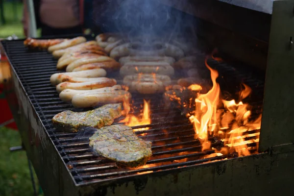 Carne e salsiccia vengono arrostiti su una grande griglia a carbone — Foto Stock