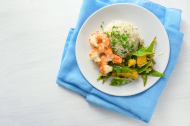 şeker bezelye ve portakal sebze ile kızarmış kaplan karides beyaz bir masada mavi bir peçete üzerinde pirinç ile servis, uzay kopyalamak, yukarıdan yüksek açı görünümü