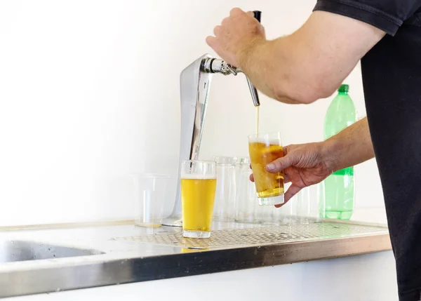 Homem está desenhando cerveja em copos de uma simples torneira em um festival ao ar livre, espaço de cópia — Fotografia de Stock