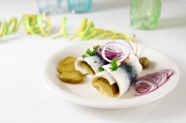 akşamdan kalma yemek, haddelenmiş ringa balığı turşusu, ayrıca kırmızı soğan, gherkins ve kapari kağıt flamalar ile beyaz bir masada rollmops denir, kopya alanı
