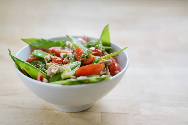 Salade saine de pois mange-tout et tomates cerises au thon dans un bol blanc sur une table en bois, espace de copie — Photo