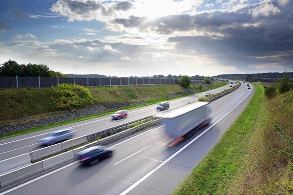 Αυτοκινητόδρομο στη χώρα με οδήγηση αυτοκίνητα και φορτηγά στην εθνική οδό στη χώρα με οδήγηση αυτοκίνητα και φορτηγά σε κίνηση θόλωση κάτω από ένα δραματικό ουρανό με σύννεφα, έννοια για την κυκλοφορία, τις μεταφορές και το περιβάλλον, αντιγραφή διαστημος — Φωτογραφία Αρχείου