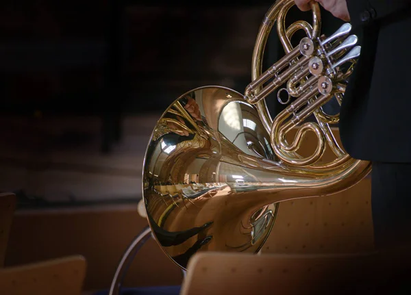 Franskt horn, musikalisk mässings instrument tillverkat av slangar lindade i en spole med en utställd klocka, före konserten med reflektioner från den gamla kyrkan, mörk bakgrund med kopierings utrymme — Stockfoto