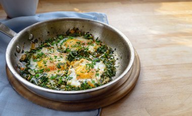 Ispanaklı ve sahanda yumurtalı tava, baharatlı ve otlu garnitür, düşük karbonhidratlı diyet için protein zengini yemek ahşap bir masada, kopyalama alanı