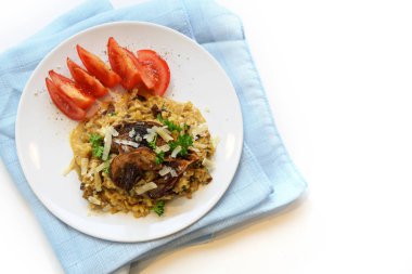 Porcini mantarlı ve domatesli karnabahar ve mavi peçeteli kremalı risotto, fotokopi alanı olan arka plan beyaza dönüyor, yukarıdan yukarıdan üst görünüm