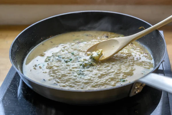 在移动炉灶上的锅子里，用木勺搅拌沸腾的戈龙佐拉奶酪酱汁，这是一个烹调的概念 — 图库照片