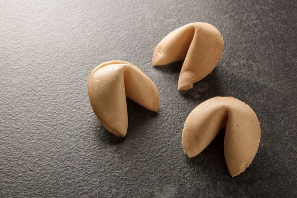 Three chinese fortune cookies on a dark gray background with copy space, selected focus, narrow depth of field — Stock Photo, Image