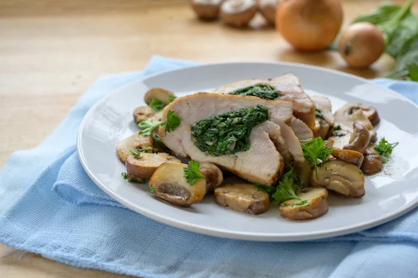 Fillet dada ayam diisi dengan bayam, disajikan dengan jamur dan hiasan peterseli pada serbet biru dan meja kayu ringan, ruang fotokopi — Stok Foto