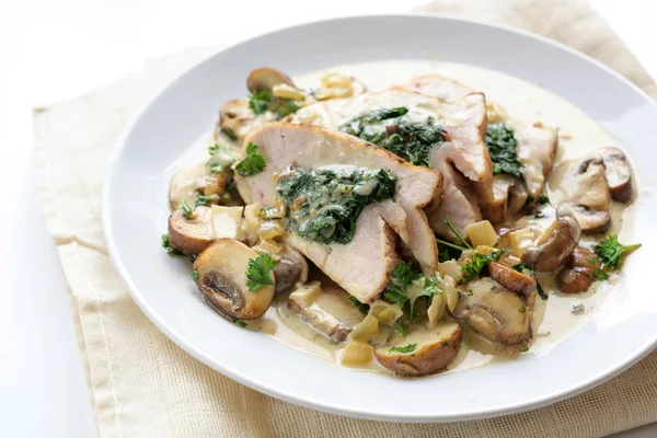 Isi fillet dada ayam dengan bayam, jamur dan saus gorgonzola krem di piring putih — Stok Foto