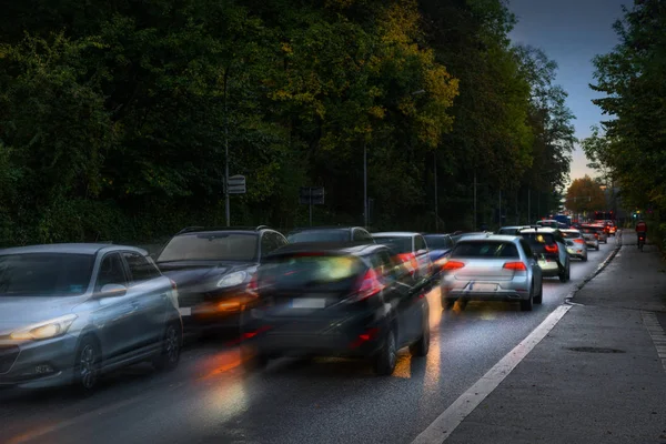 Braking cars at rush hour jam in a dark narrow street to town with wet asphalt on the way to business work early in the morning, motion blur, copy space — Stock Photo, Image