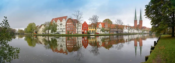 Cityscape, old town of Luebeck in Germany, wide panoramic view from the famous Malerwinkel, that means painter's corner, to the historic city at the river Trave with reflections, copy space in the cloudy blue sky — Stock Photo, Image