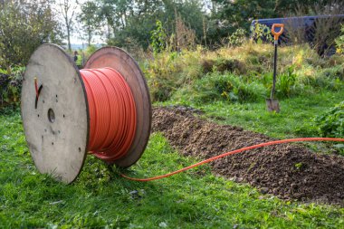 Hızlı internet için fiber optik kabloyla ahşap makara. Yerdeki dar siperlere yerleştirilmeye hazır. Kırsal alanda altyapı genişlemesi.