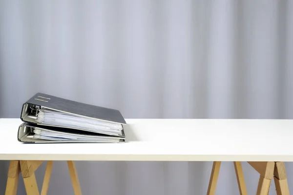 Twee ringbanden op een eenvoudig wit bureau op houten rekken, grijze achtergrond met kopieerruimte, kantoor- of bedrijfsconcept — Stockfoto