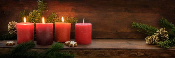 Third Advent, three of four red candles are lit with a flame, fir branches and Christmas decoration on dark rustic wood, wide panoramic format with copy space — Stock Photo, Image