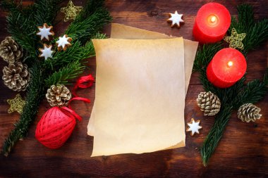 Köknar dalları, yanan mumlar, tarçın yıldızları, koniler ve kırsal kesimlerdeki Noel süslemeleri arasındaki boş kağıt çarşaf, kopyalama alanı, yukarıdan üst görünüm