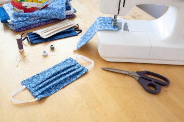 Dikiş makinesi, makas, iplik ve araç gereçleri ile koronavirüs salgını sırasında enfeksiyona karşı maske yapmak ahşap bir masa üzerinde, kopyalama alanı, seçili odak, dar alan derinliği