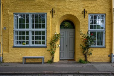 Almanya 'nın başkenti Luebeck' in merkezinde Muntin pencereli ve kemerli tarihi bir kasaba evinin sarı cephesi.
