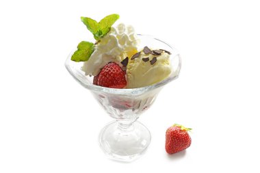 Dondurmalı tatlı, taze çilek, çırpılmış krema ve naneli garnitür cam bir kadehte, beyaz arka planda gölgelerle izole edilmiş, uzay kopyası.