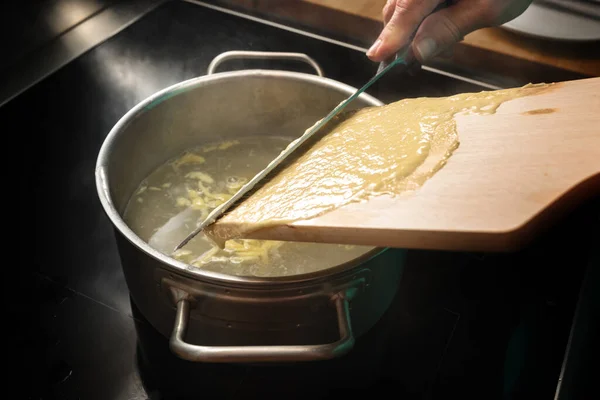 自家製の卵パスタ生地を木製の板から熱湯に廃棄し シュヴァーベン 南ドイツ オーストリアの典型的な料理 ナイフに焦点を当て フィールドの狭い部分を選択します — ストック写真
