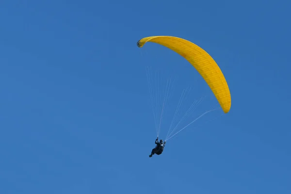 黄色のグライダーとパラグライダーのパイロットは 澄んだ青い空 レクリエーション 競争力のあるアドベンチャースポーツ コピースペースを飛んでいます — ストック写真