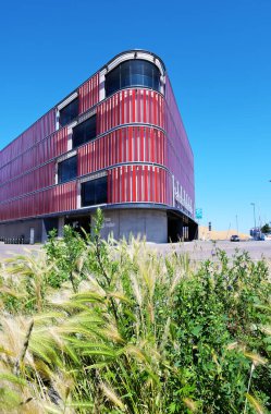 Wismar, Almanya, 16 Haziran 2020: Wismar, Almanya 'nın eski ahşap limanında çok katlı bir otopark, modern mimari mavi gökyüzüne karşı vahşi bir çayırın arkasında.