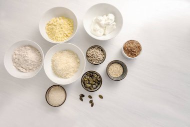 Kuark, yulaf kepeği, badem unu ve beyaz bir masada çeşitli tohumlarla sağlıklı düşük karbonhidratlı protein ekmeği pişirmek, yukarıdan yüksek açılı görüş alanı kopyalamak.