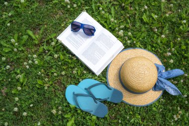 Bahçede vakit geçirmek, kitap, hasır şapka, güneş gözlüğü ve parmak arası terlik, Coronavirus salgını sırasında evde tatil, fotokopi alanı, yukarıdan yüksek açı, seçilmiş odak noktası.