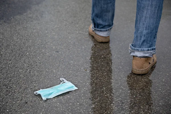 Medical Face Mask Discarded Wet Asphalt Man Legs Walk Away — Stock Photo, Image