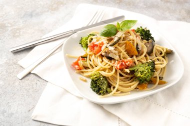 Brokolili vejetaryen spagetti, domates, dolma biber ve patlıcan, beyaz tabakta sağlıklı Akdeniz makarnası yemeği ve sade bir arka plan, fotokopi alanı, seçilmiş alan, dar alan derinliği