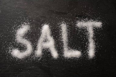 Tuz kristalleri ile yazılan Kelime SALT koyu bir levha, yukarıdan yüksek açı görünümü, seçili odak