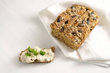 Beyaz bir masada krem peynirli ve maydanozlu protein ekmeği, düşük karbonhidrat veya ketojenik diyet ile inceltilerek yukarıdan yüksek açılı görüş, kopyalama alanı, seçilmiş odaklanma alanı