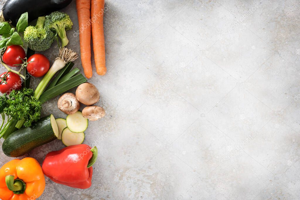 Colorful organic vegetables on the side of a light gray surface with large copy space, healthy kitchen background, high angle view from above