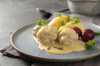 Koenigsberger Klopse ya da kapari, patates ve pancar soslu beyaz beşamel soslu köfteler gri bir tabakta servis edilir, geleneksel Polonya ve Alman yemeği, kopyalama alanı, seçilmiş alan, dar alan derinliği