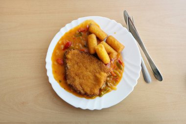 Malzemelerden matara, dolma biber soslu şnitzel ve beyaz tabakta patates kroketleri, fotokopi alanı, yukarıdan görüş.