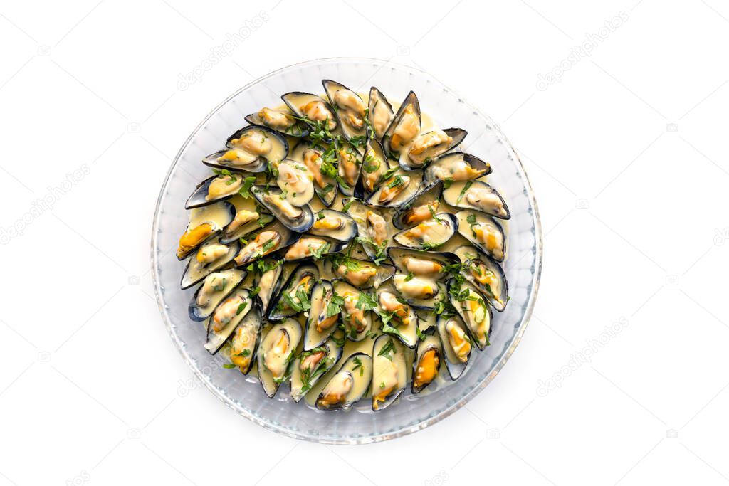 Blue mussels with white wine sauce, onions, garlic and parsley garnish served on a large glass plate, isolated on a white background, high angle view from above
