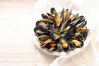 Parlak ahşap bir masada beyaz bir tabakta servis edilen taze mavi midyeler, kopyalama alanı, seçilmiş odak, dar alan derinliği