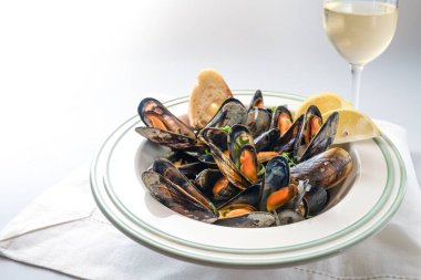 Maydanozlu, limonlu ve ekmekli midye, beyaz bir masada şarap kadehi ve peçete, kopya alanı, seçilmiş odak, dar bir alan derinliği