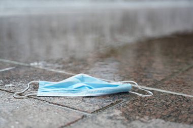 Sokağın ortasında yağmurda yatan kovid 19 'a karşı cerrahi yüz maskesi, koronavirüs salgını yeni atık türleri yaratıyor, çevresel hasara ve atık sorunlarına yol açıyor, kopyalama alanı, seçilmiş alan, dar alan derinliği